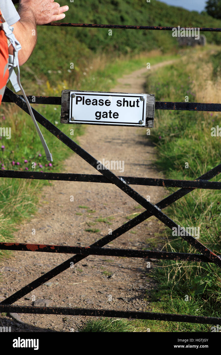 Please Shut Gate sign on country path with mans hand closing it over. Stock Photo