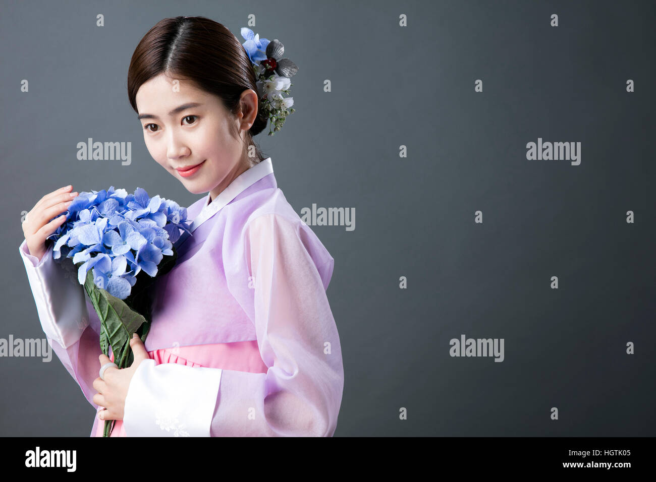 Side view of smiling woman in traditional Korean clothes holding ...