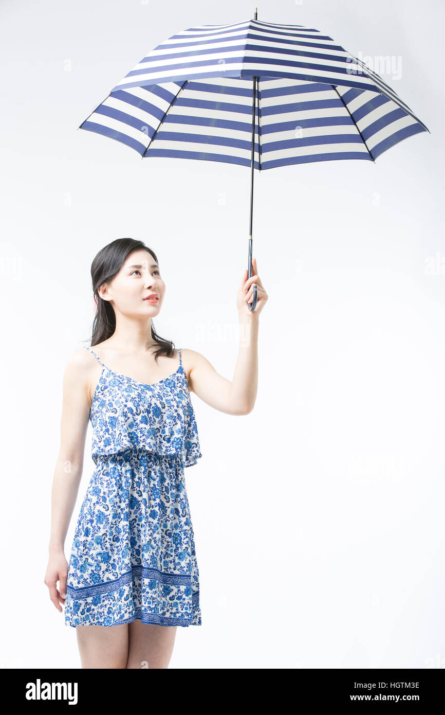 Young woman in summer dress holding an umbrella looking up Stock Photo