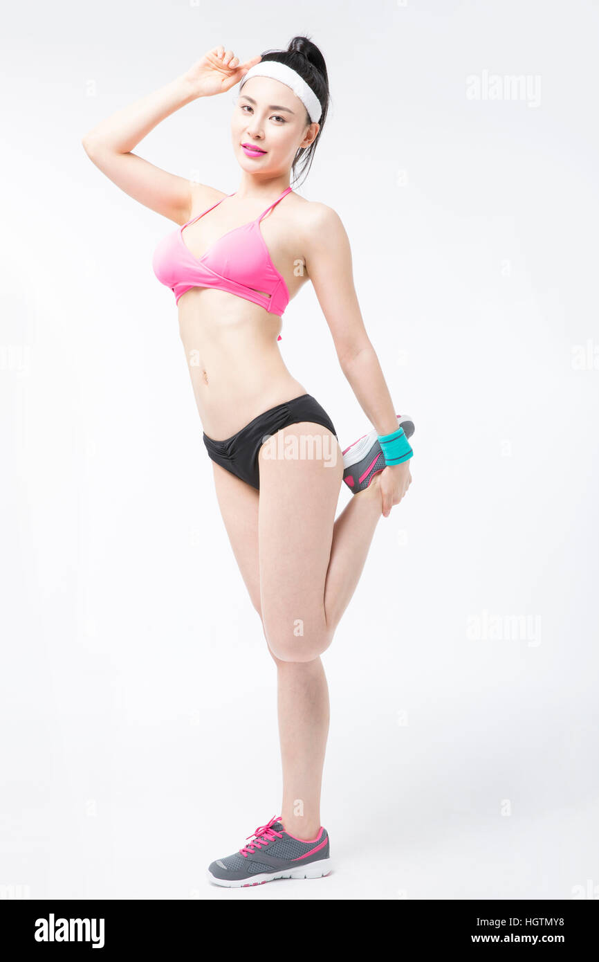 Young slim woman in bikini stretching leg Stock Photo - Alamy