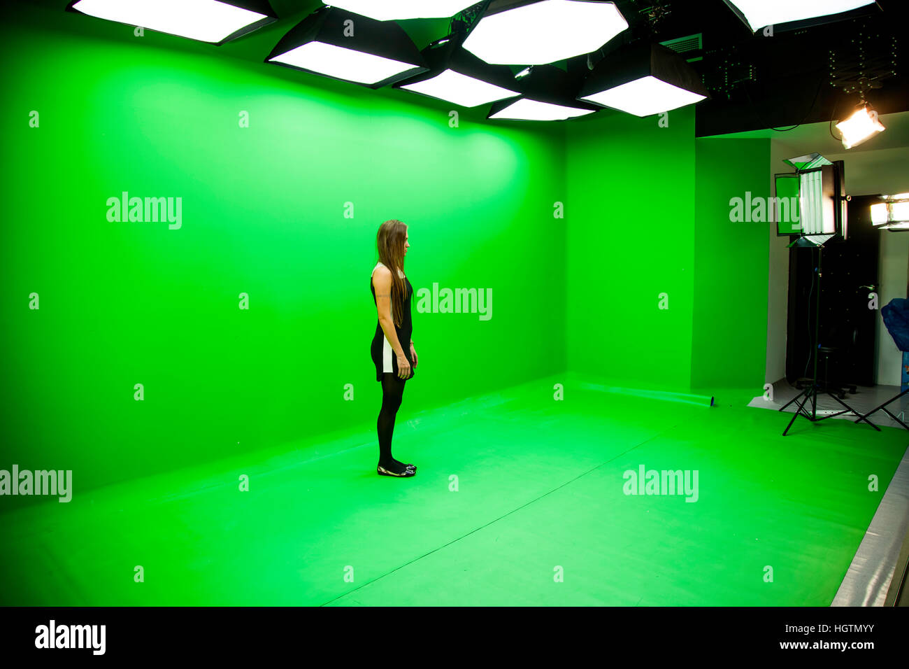 photography studio with a green background and a lady standing in middle Stock Photo