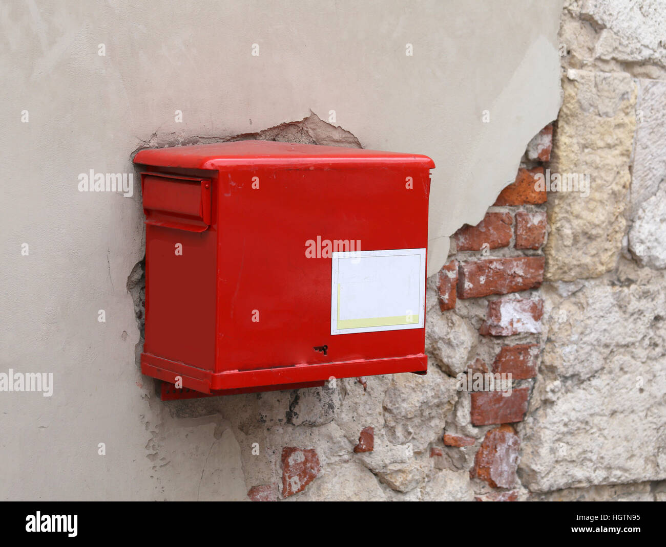 old red mailbox on the peeling wall Stock Photo