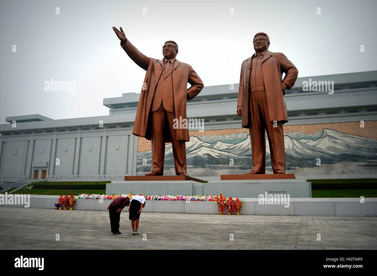 Two North Korean women pay their respects to the statues of Kim Il Sung (left) and Kim Jong Il (right). July 1, 2012. Stock Photo