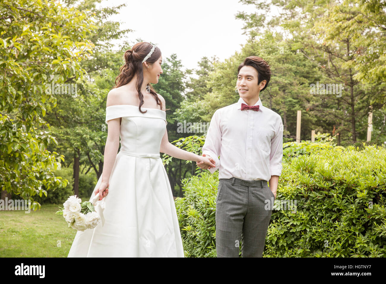 Young smiling wedding couple holding hands face to face outdoors Stock Photo