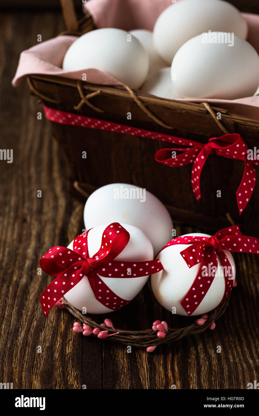 White easter eggs with red bows on rustic background Stock Photo - Alamy