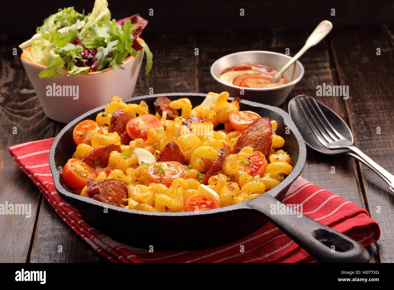Casserole with chorizo sausage in a frying pan on wooden background