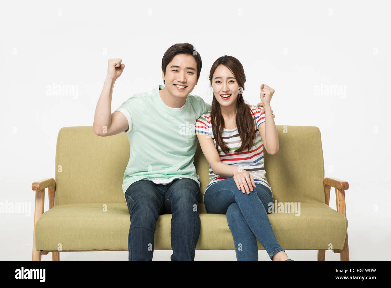Young smiling couple cheering watching a game on TV Stock Photo