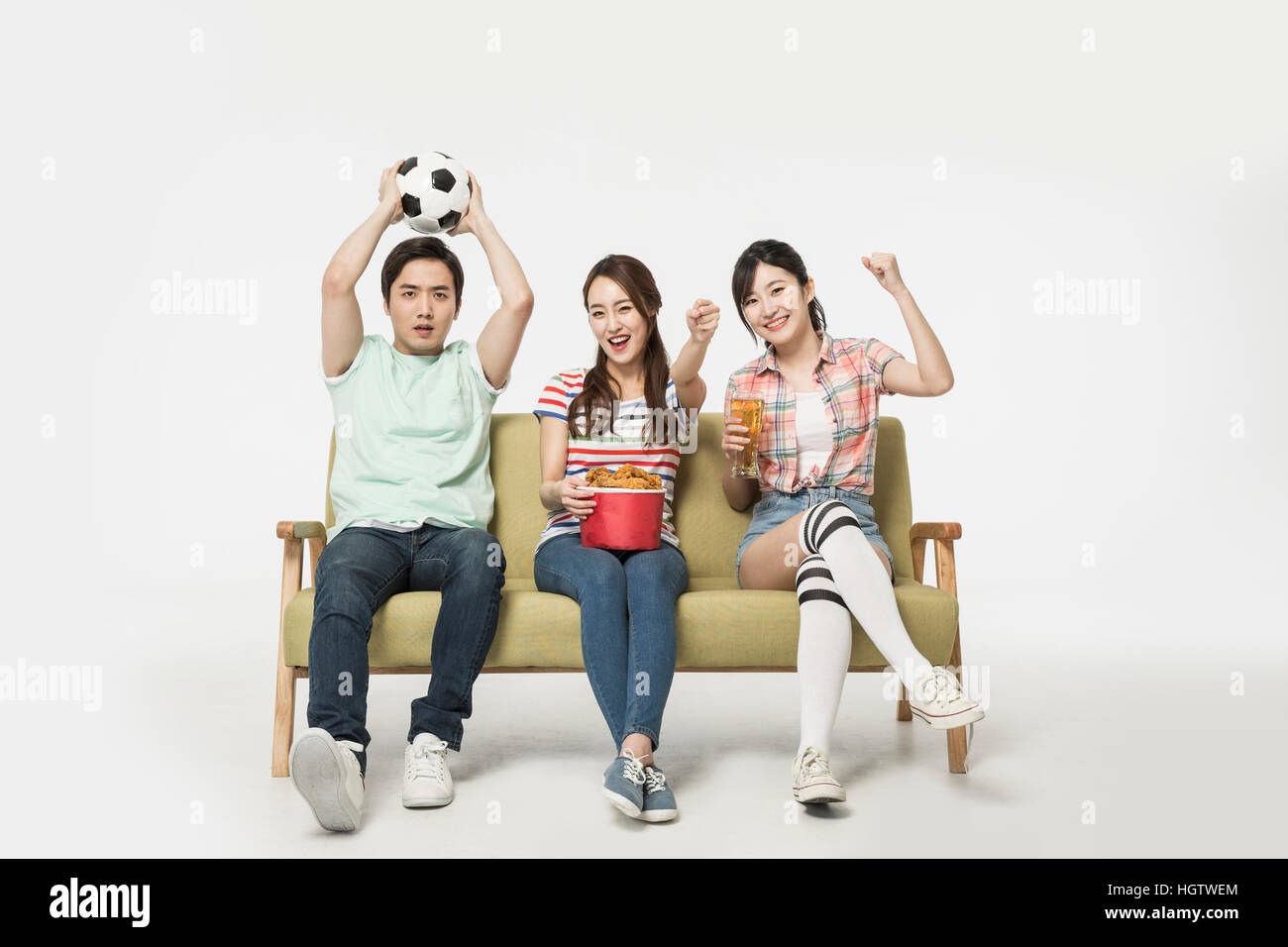 Young smiling people cheering watching a game on TV Stock Photo
