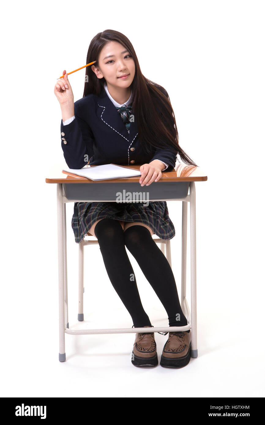 Smiling high school girl with a pencil sitting at desk thinking Stock ...