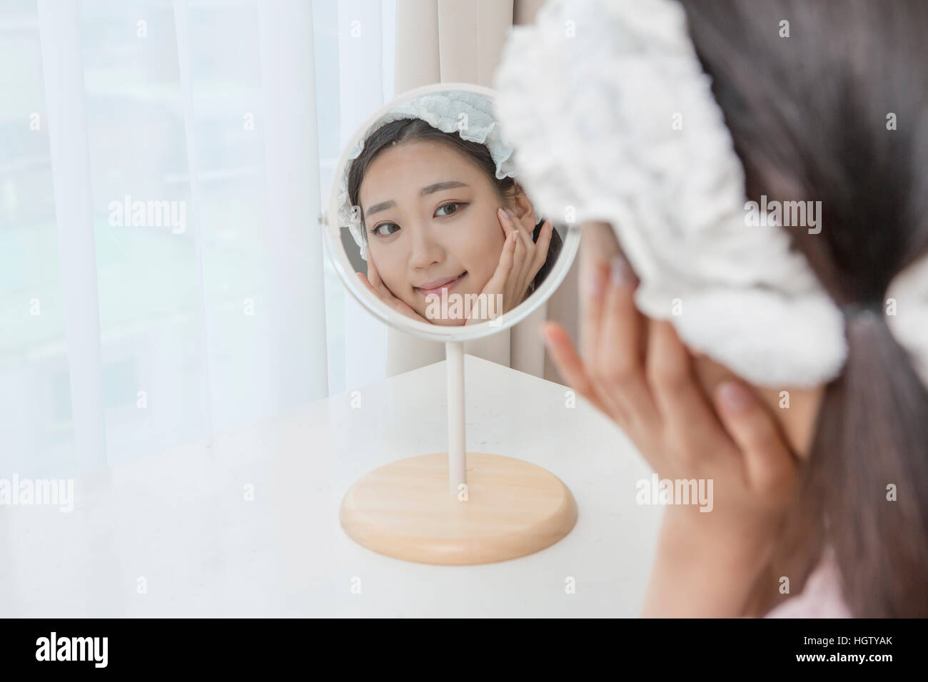 Portrait of young woman touching her face looking in mirror Stock Photo ...