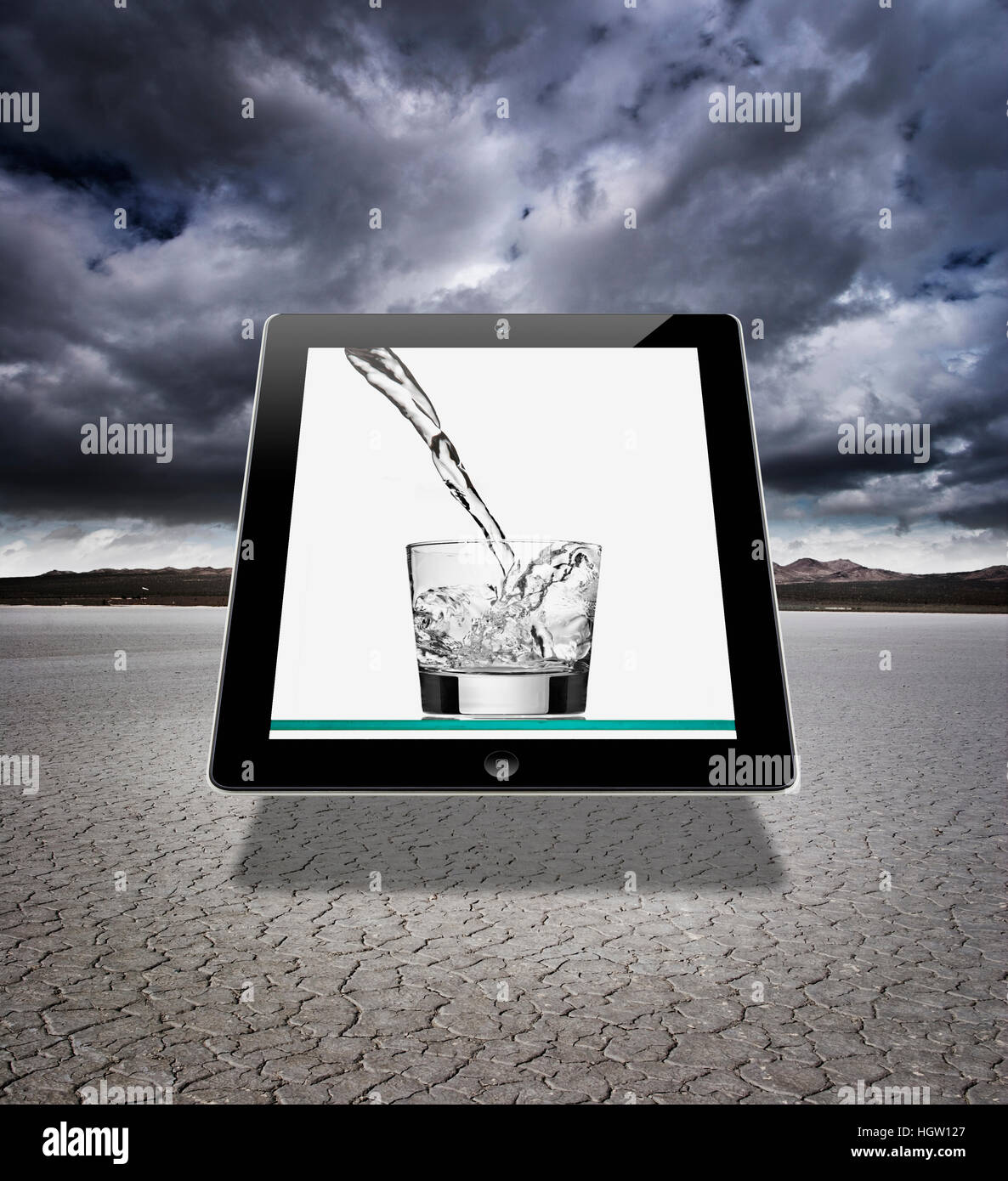 A Digital Tablet In A Dry Lake Bed With An Image Of A Glass Of Water Being Poured. Stock Photo