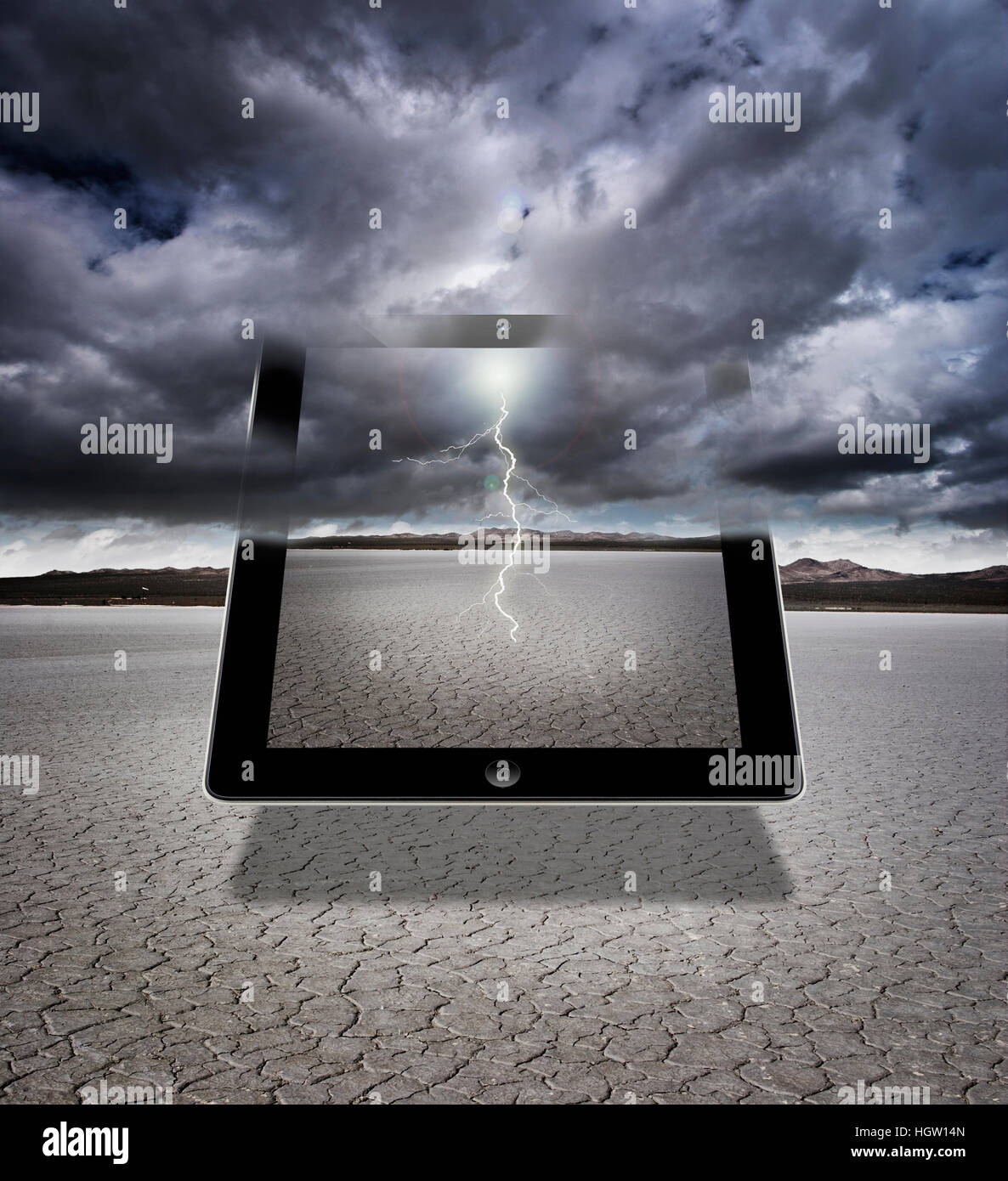 Composite Of A Digital Tablet With Storm Clouds And Lightning In A Dry Lakebed Stock Photo