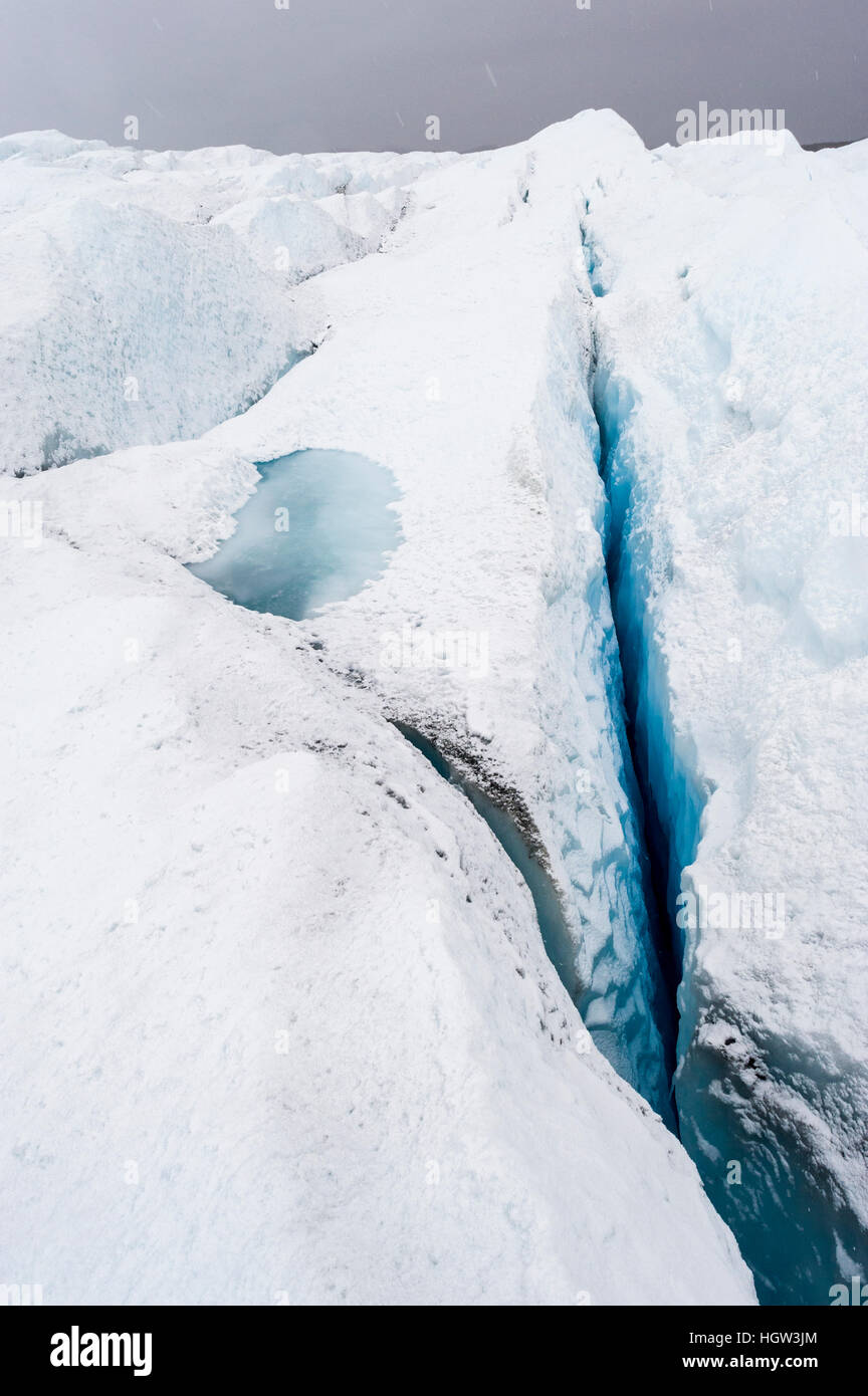 Pressure ridges and crevasse scar the surface of a glacier on the Greenland Ice Sheet. Stock Photo