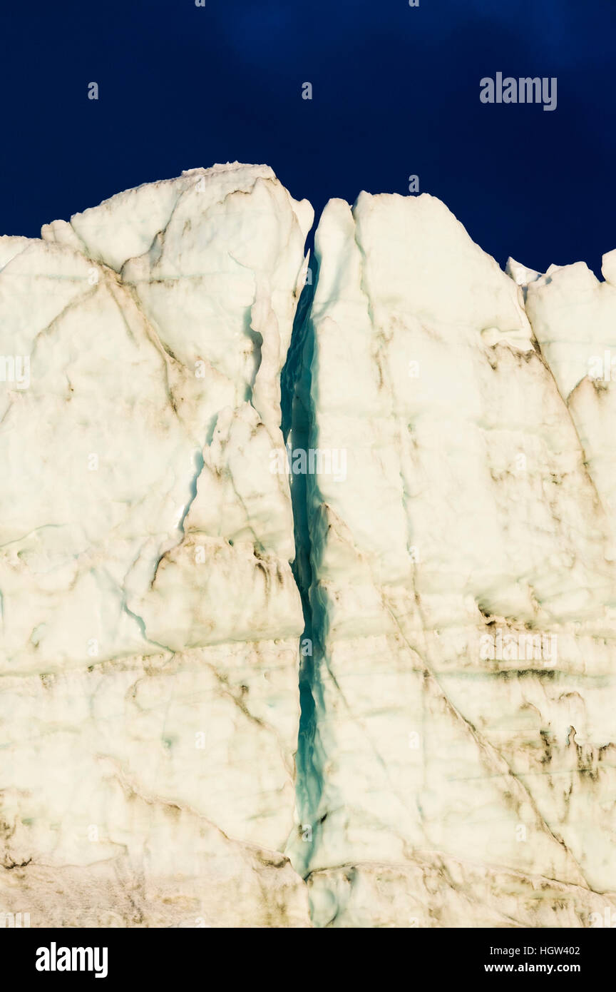 The setting sun illuminates a crevasse in the sheer ice cliff of a glacier fracture zone. Stock Photo