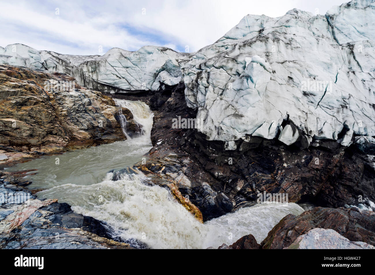 A waterfall of meltwater cascades from beneath a glacier fracture zone. Stock Photo
