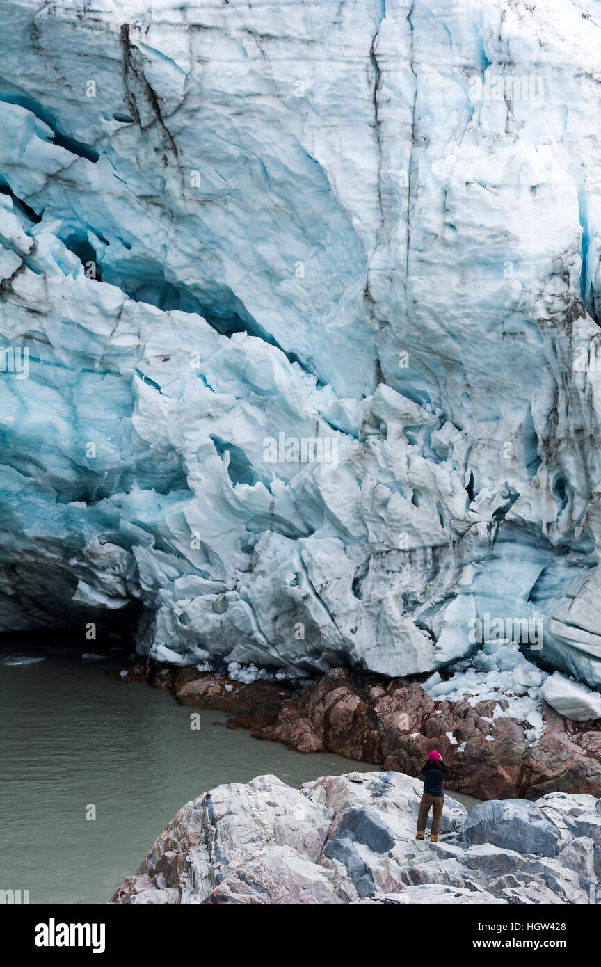 A hiker photographs a glacier fracture zone from a dangerous position beneath the ice. Stock Photo