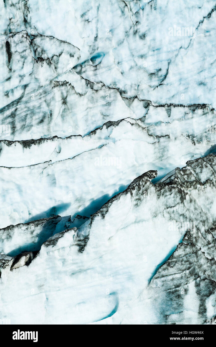 Erosion from ice against rock deposits silt and soil sediment on the edges of ice blades along the fracture zone of a glacier. Stock Photo