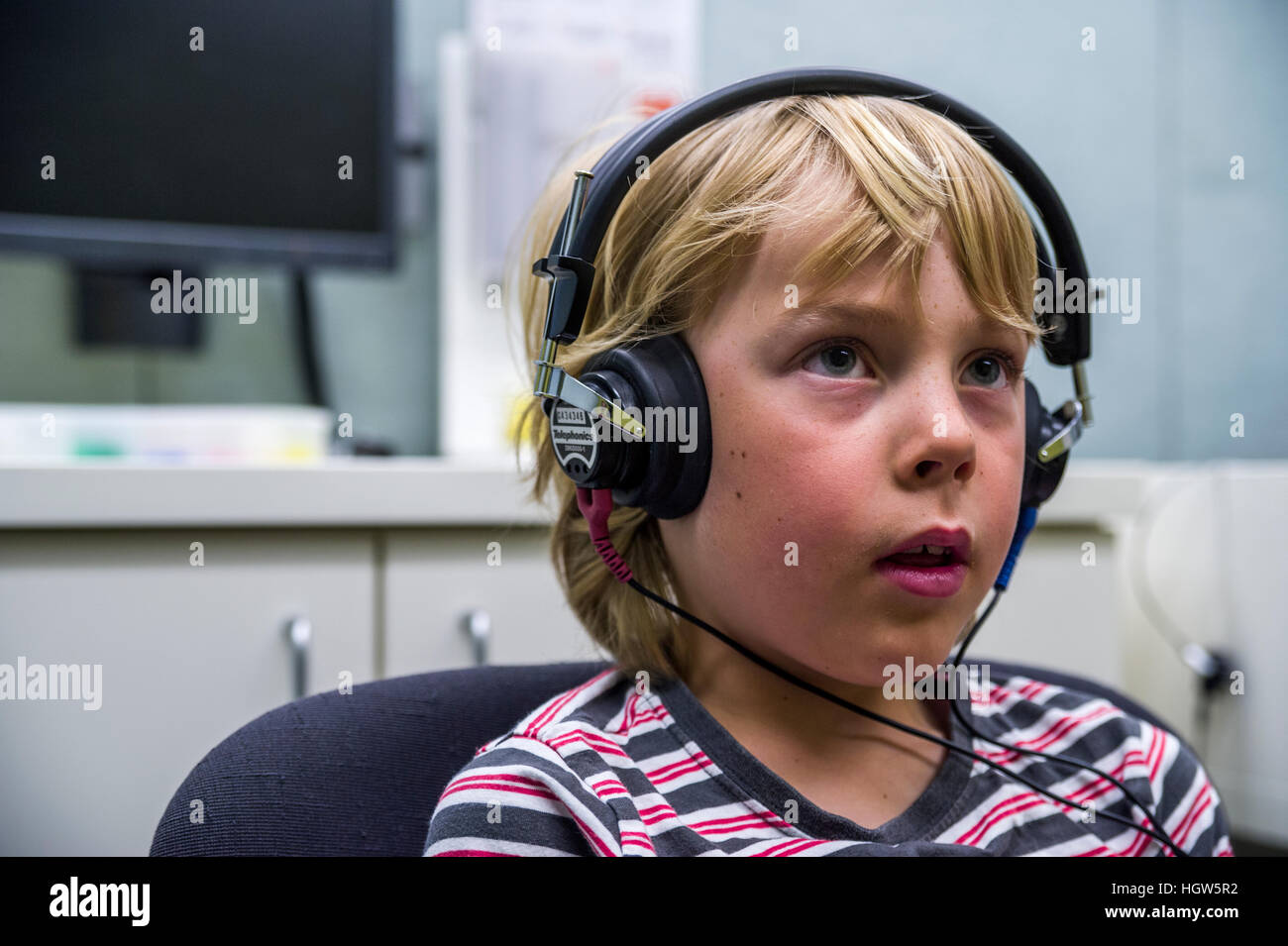 A boy concentrating whilst he listens for sounds in headphones during a hearing test in an audiologist clinic. Stock Photo