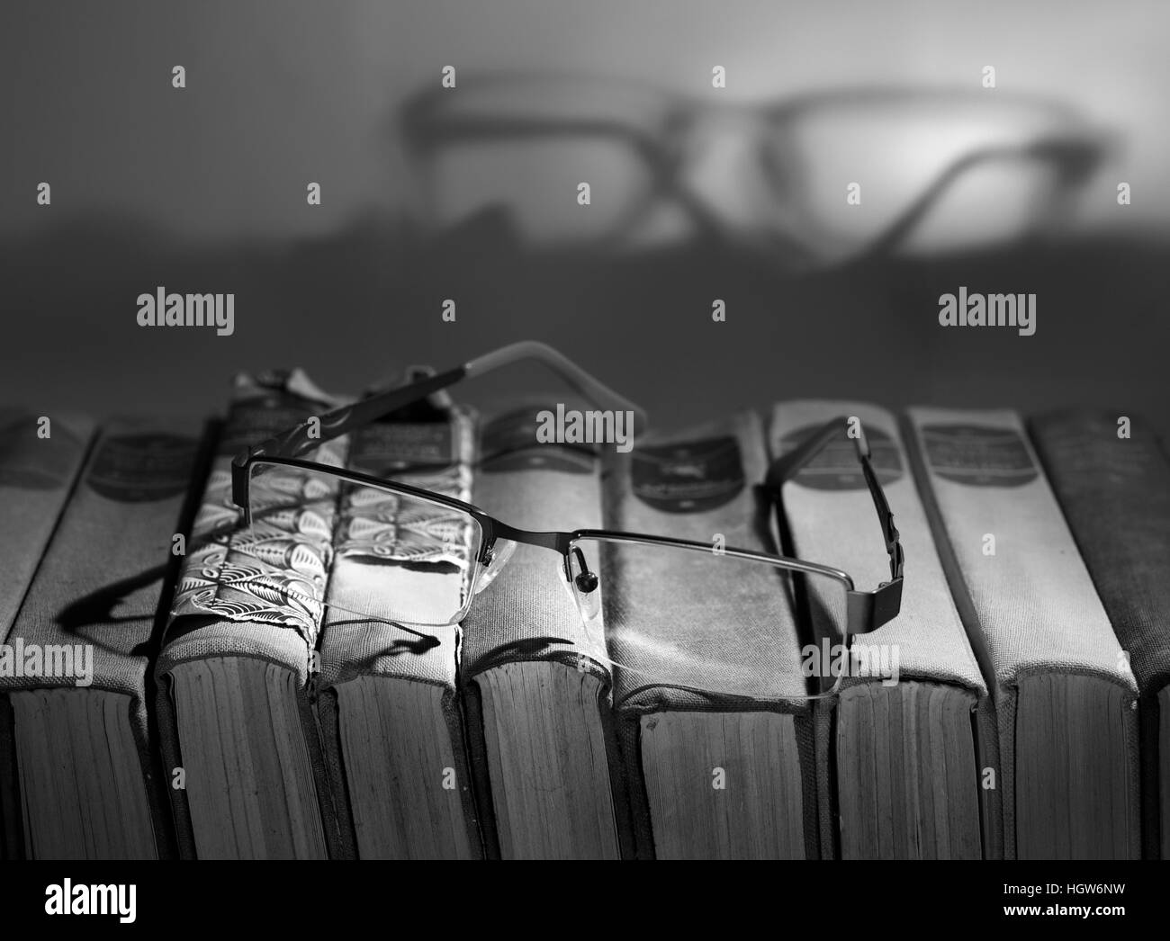Reading concept. Pair of glasses on a stack of books (black and white) Stock Photo