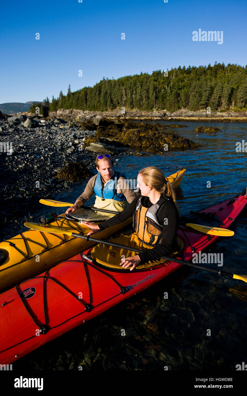 A young couple sea kayaking near the Porcupine Islands in Maine's