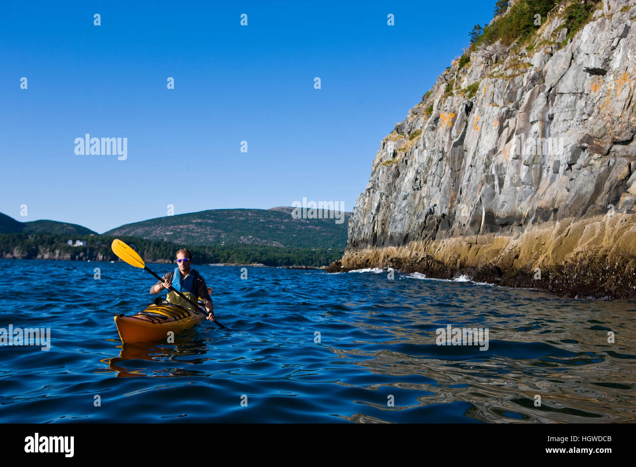 A man sea kayaking near Bald Porcupine Island in Maine's Acadia