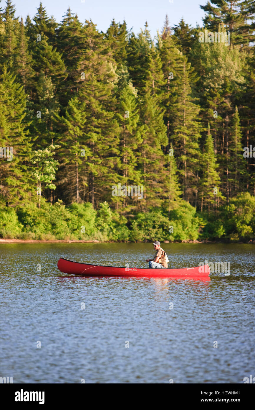 A man flyfishing from a canoe on Little Greenough Pond in Errol, New