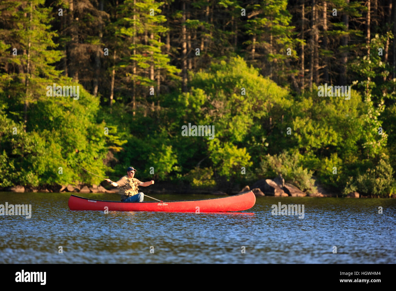 A man flyfishing from a canoe on Little Greenough Pond in Errol, New