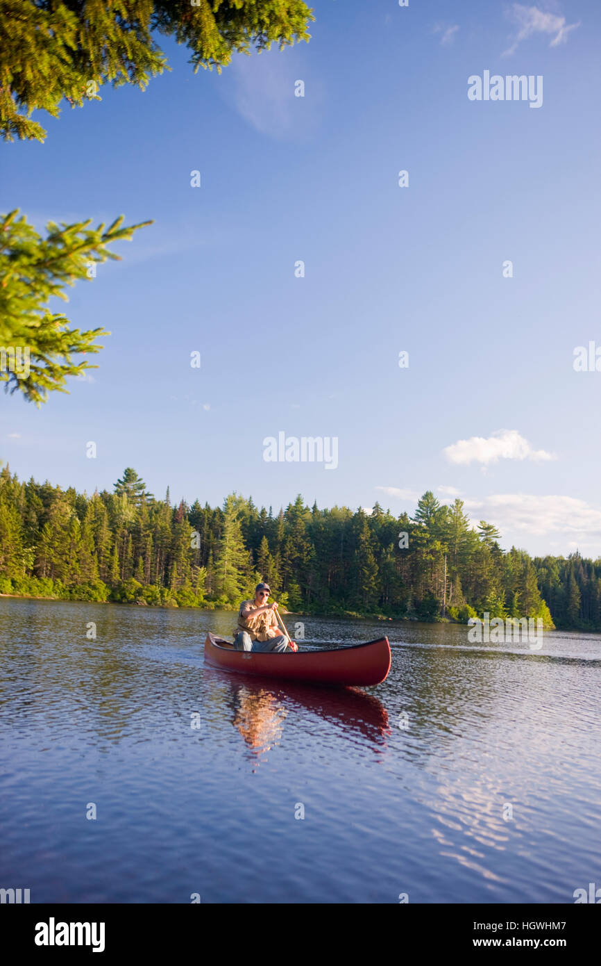 A man flyfishing from a canoe on Little Greenough Pond in Errol, New