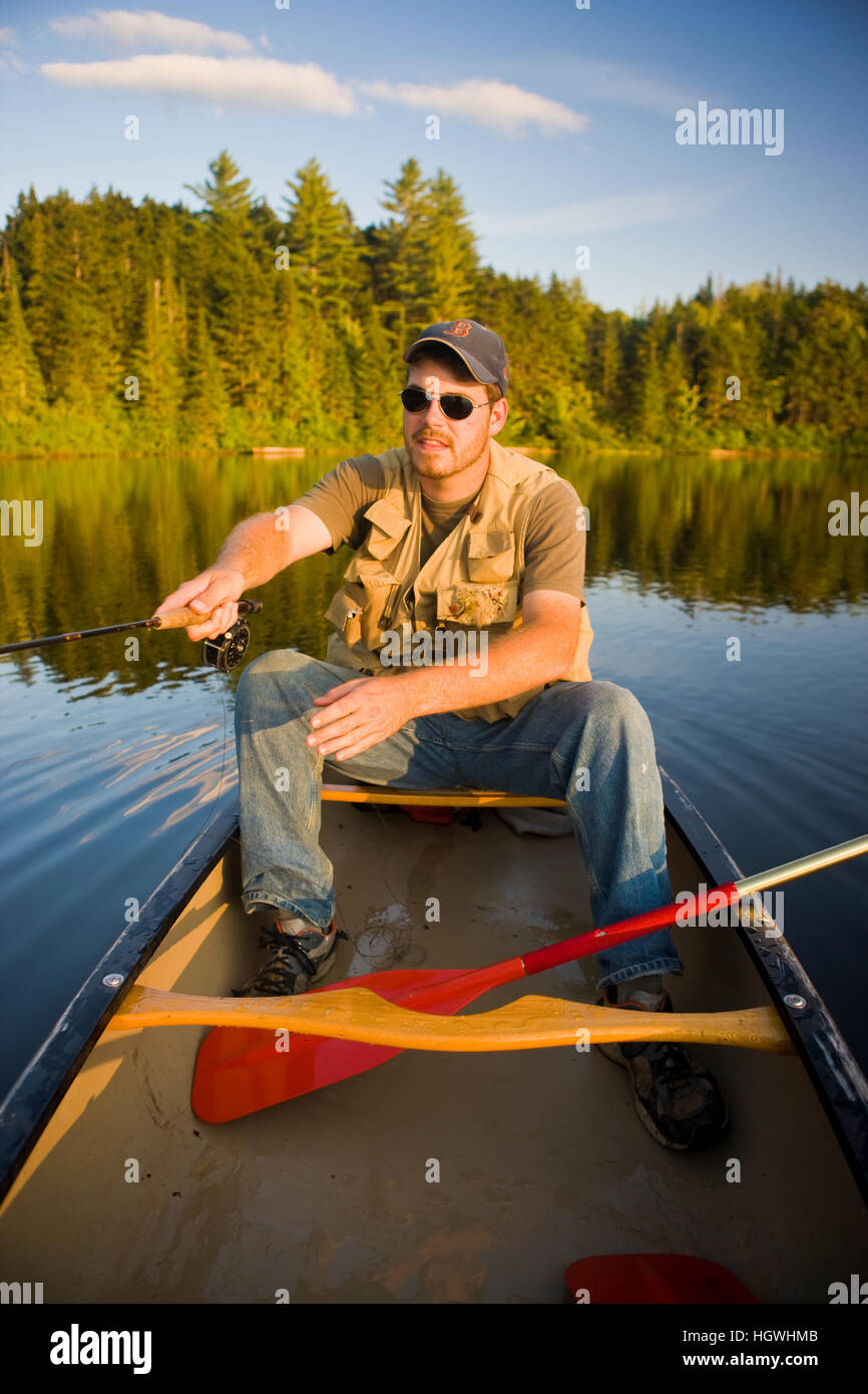 A man flyfishing from a canoe on Little Greenough Pond in Errol, New