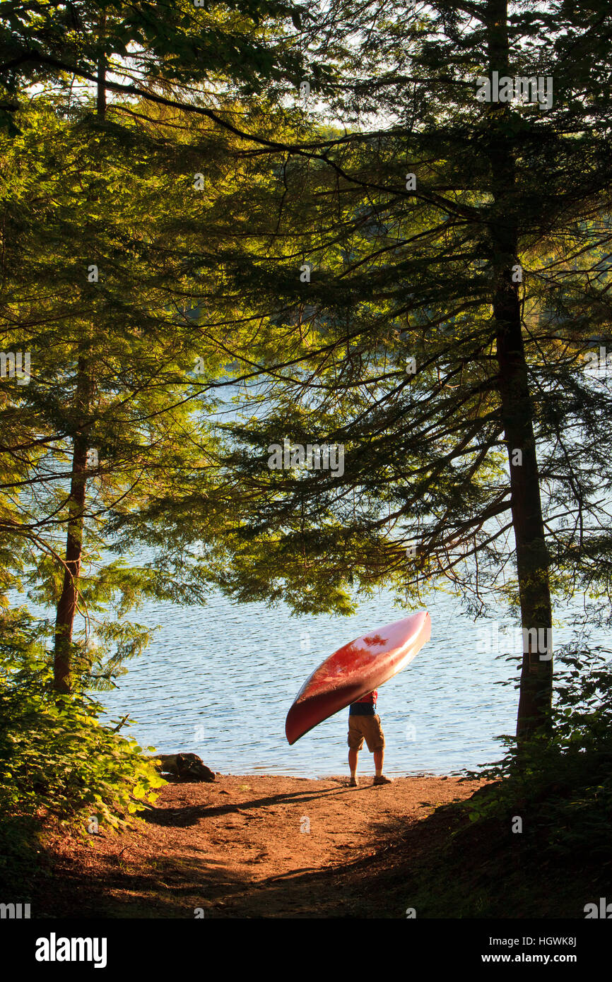 A man next to his canoe at Zack Woods Pond, Hyde Park, Vermont.  Early morning. Stock Photo