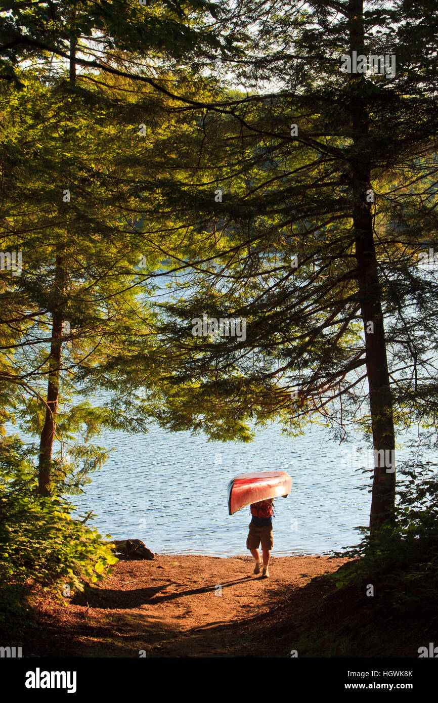 A man next to his canoe at Zack Woods Pond, Hyde Park, Vermont.  Early morning. Stock Photo