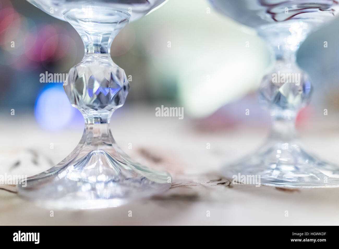 Macro closeup of two crystal wine glasses legs with blue bokeh lights Stock Photo