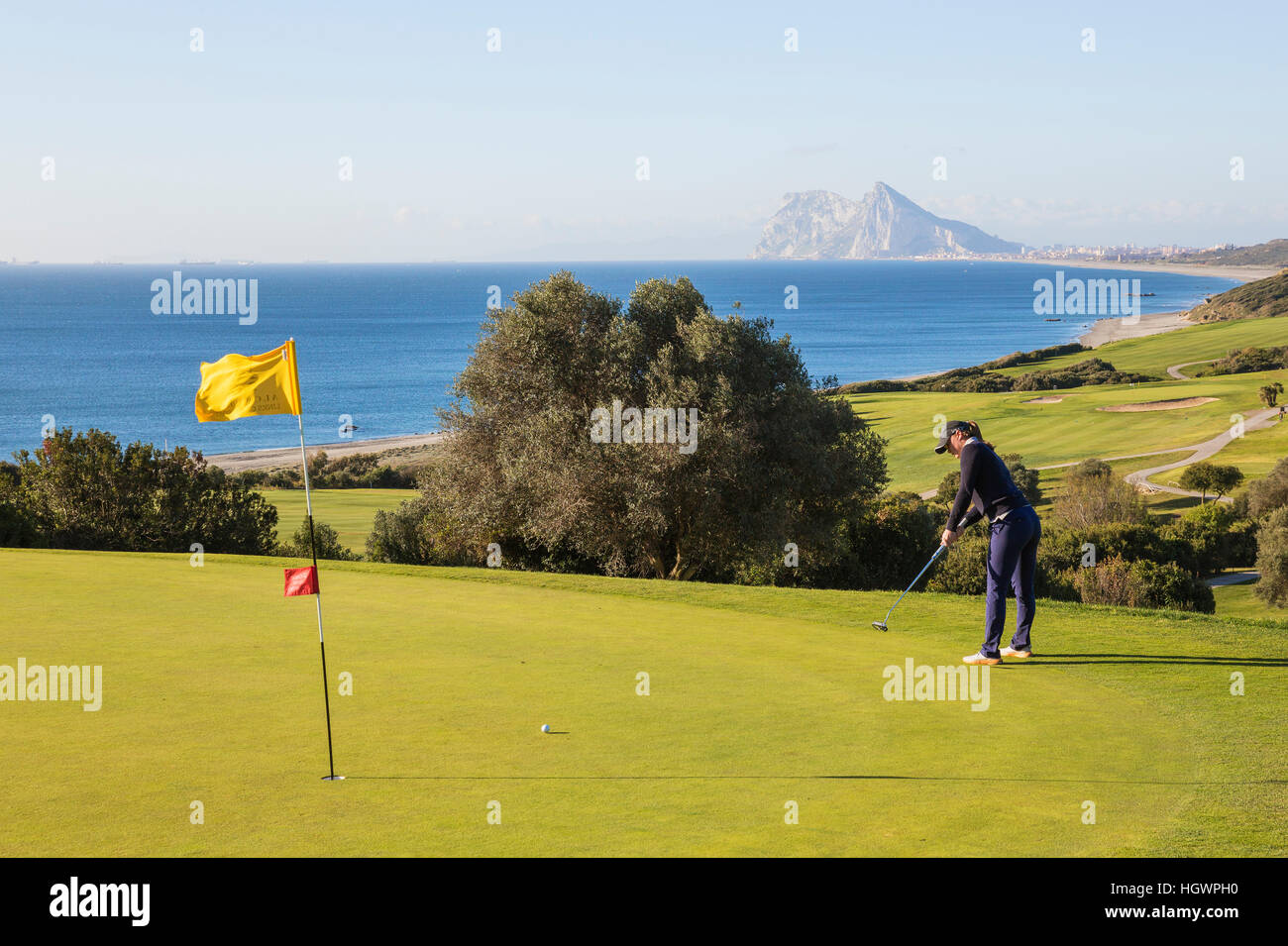 Golfer putting on green, La Alcaidesa Golf Resort with Mediterranean Sea and Rock of Gibraltar, Cádiz, Andalusia, Spain Stock Photo