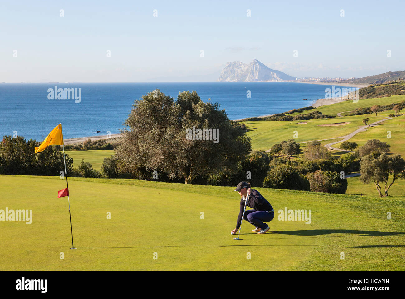 Golfer on putting green, La Alcaidesa Golf Resort with Mediterranean Sea and Rock of Gibraltar, Cádiz, Andalusia, Spain Stock Photo
