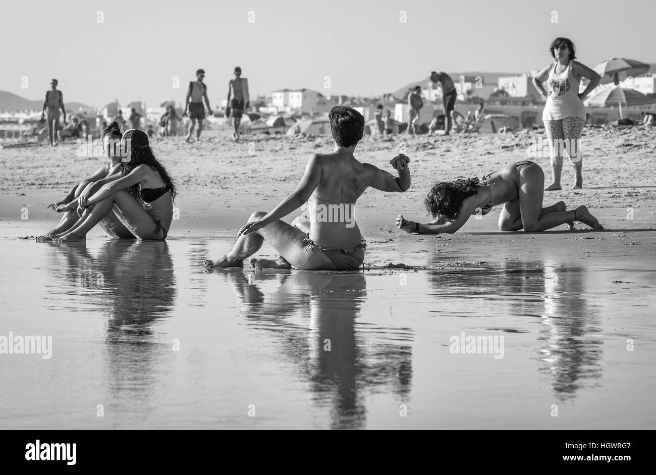 A group of teenagers in bathing suits sitting in water at sunset; Tarifa,  Cadiz, Andalusia, Spain - Stock Photo - Dissolve