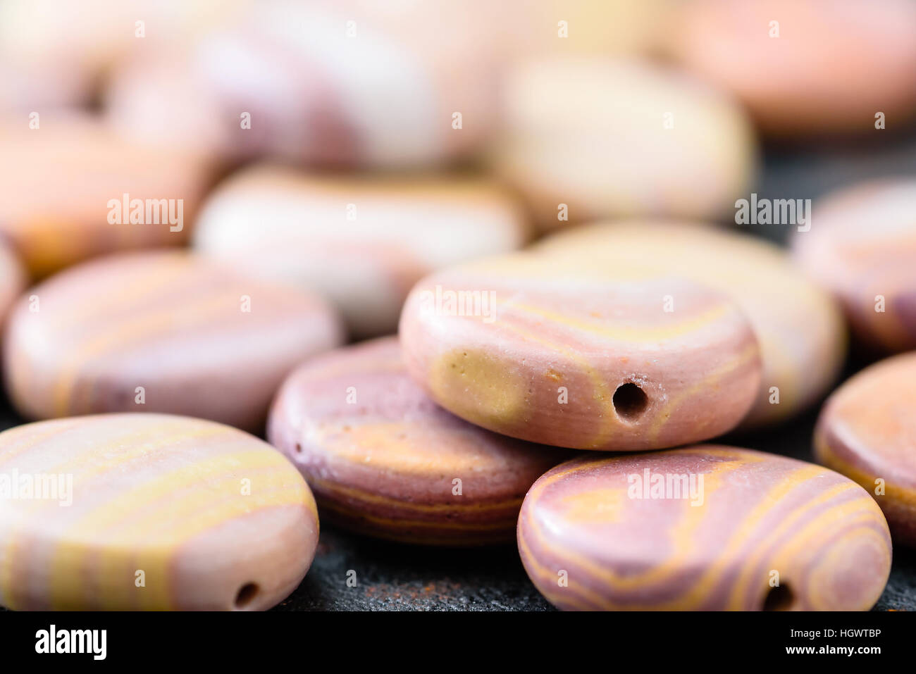 Collection of multicolored coin shaped hickoryite beads on black cast