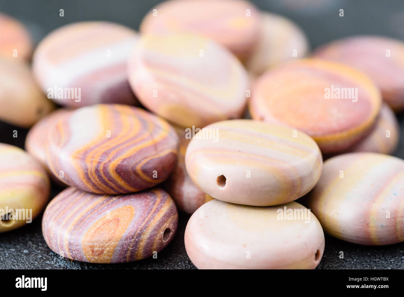 Collection of multicolored coin shaped hickoryite beads on black cast
