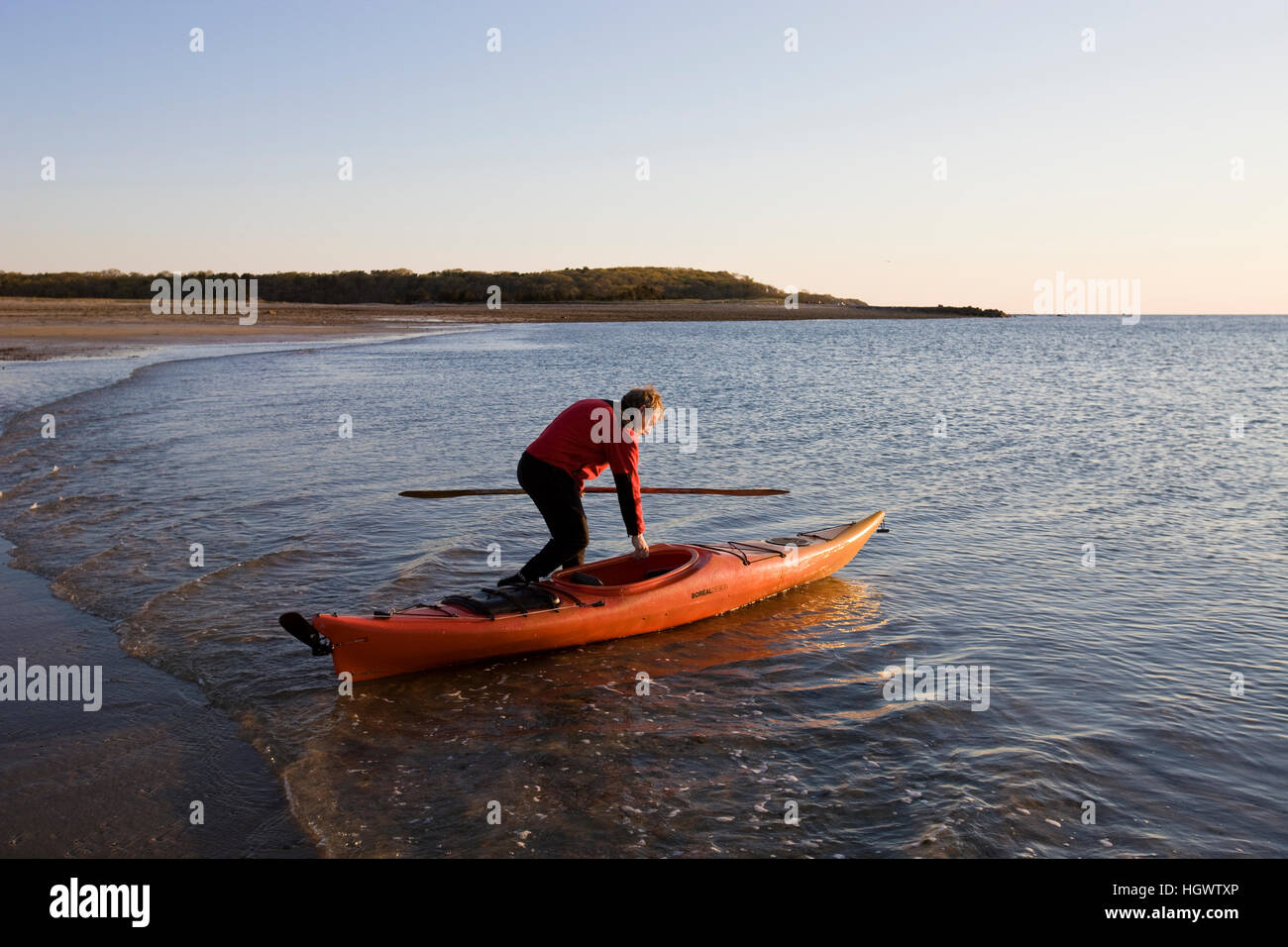 A man sea kayaking at dawn at the Shifting Lots Preserve in Plymouth, Massachusetts. Owned by