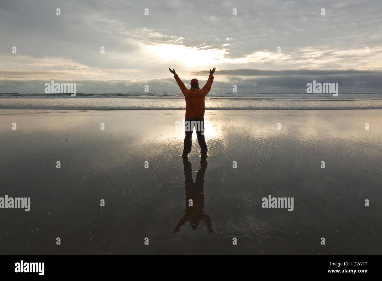 OR02325-00...OREGON - Person expressing feeling on Canon Beach at sunset. Stock Photo