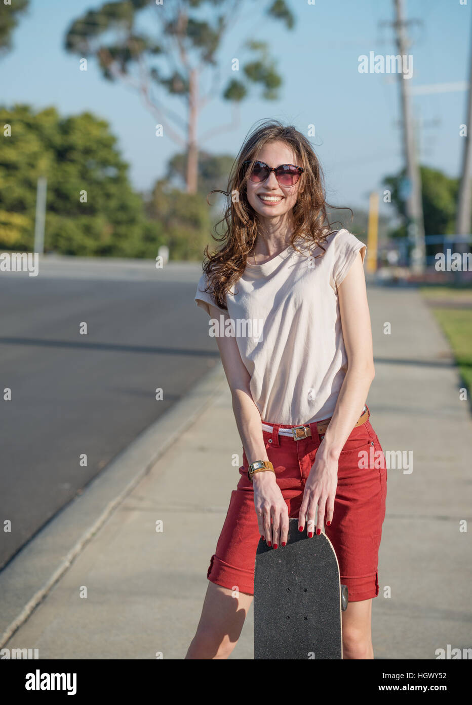 Beautiful young woman with skateboard  in the evening light Stock Photo