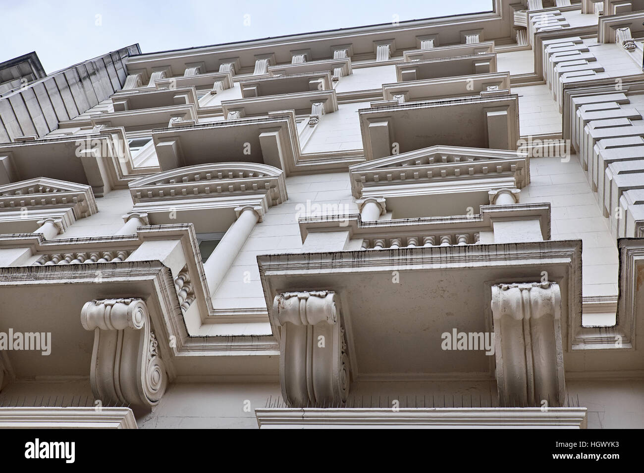 Sections of a plastered facade with elaborate decorations around the windows and balconies of a building in London City Stock Photo