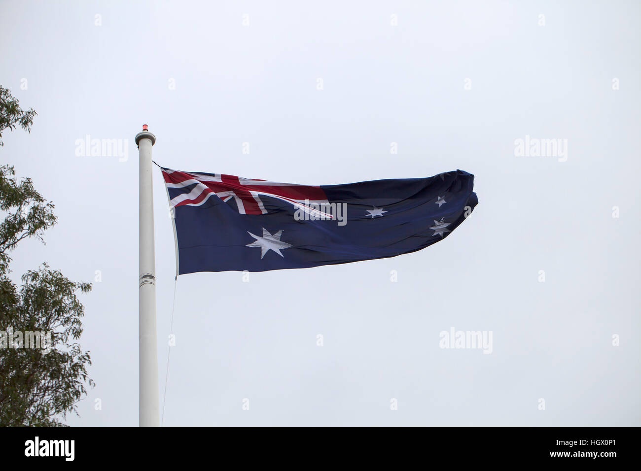 The Australian Flag. Hoist on a large flag pole in a reserve, a large  Australian flag is blown about by the wind Stock Photo - Alamy
