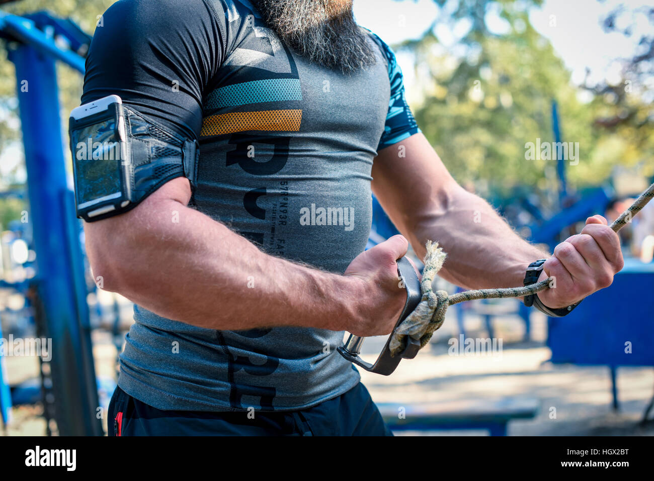 Cropped shot of muscular man using armband for smartphone during exercising outdoors Stock Photo