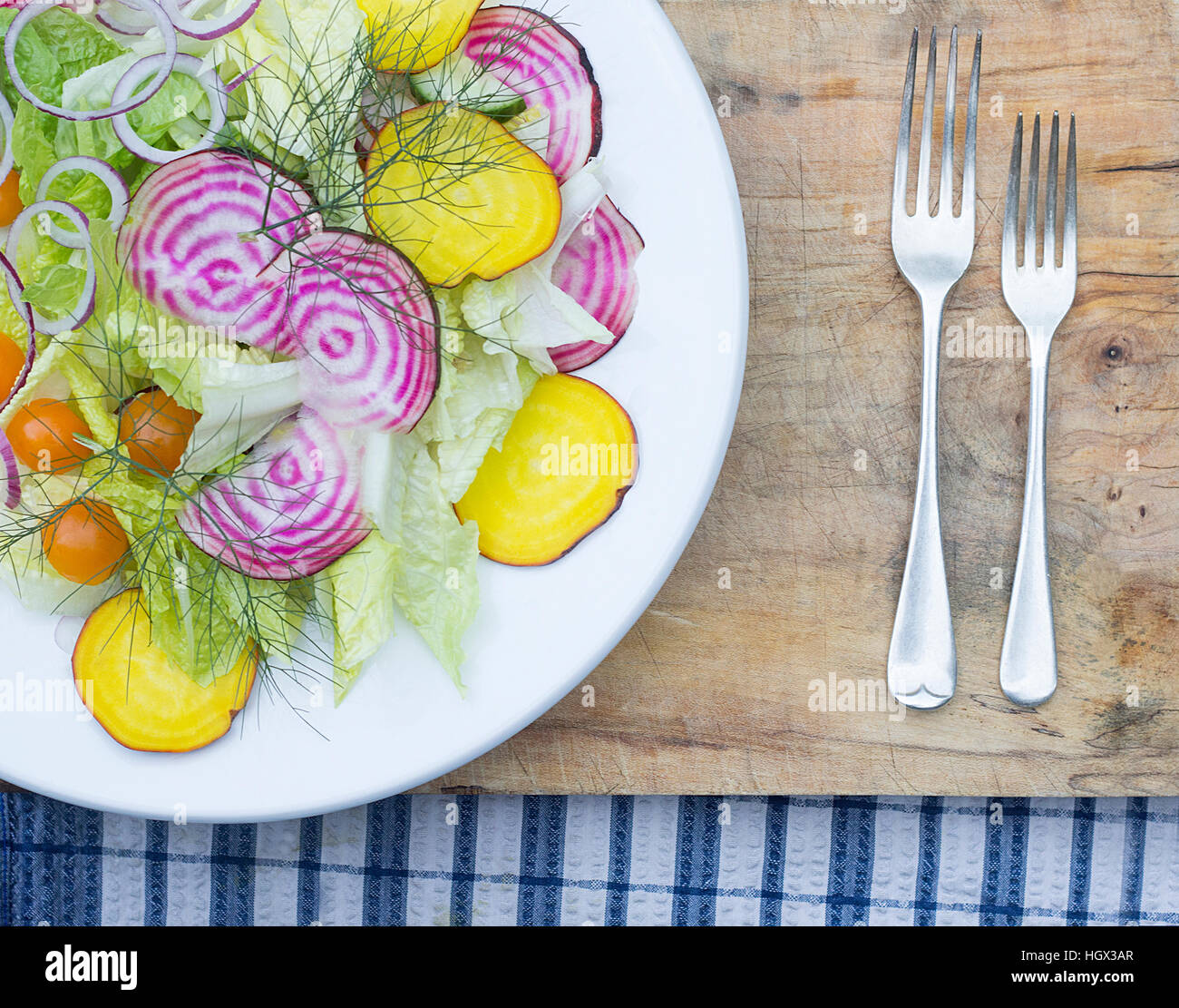 Beetroot Salad on white plate, wooden board and chequered cloth. With Antique cutlery. Stock Photo