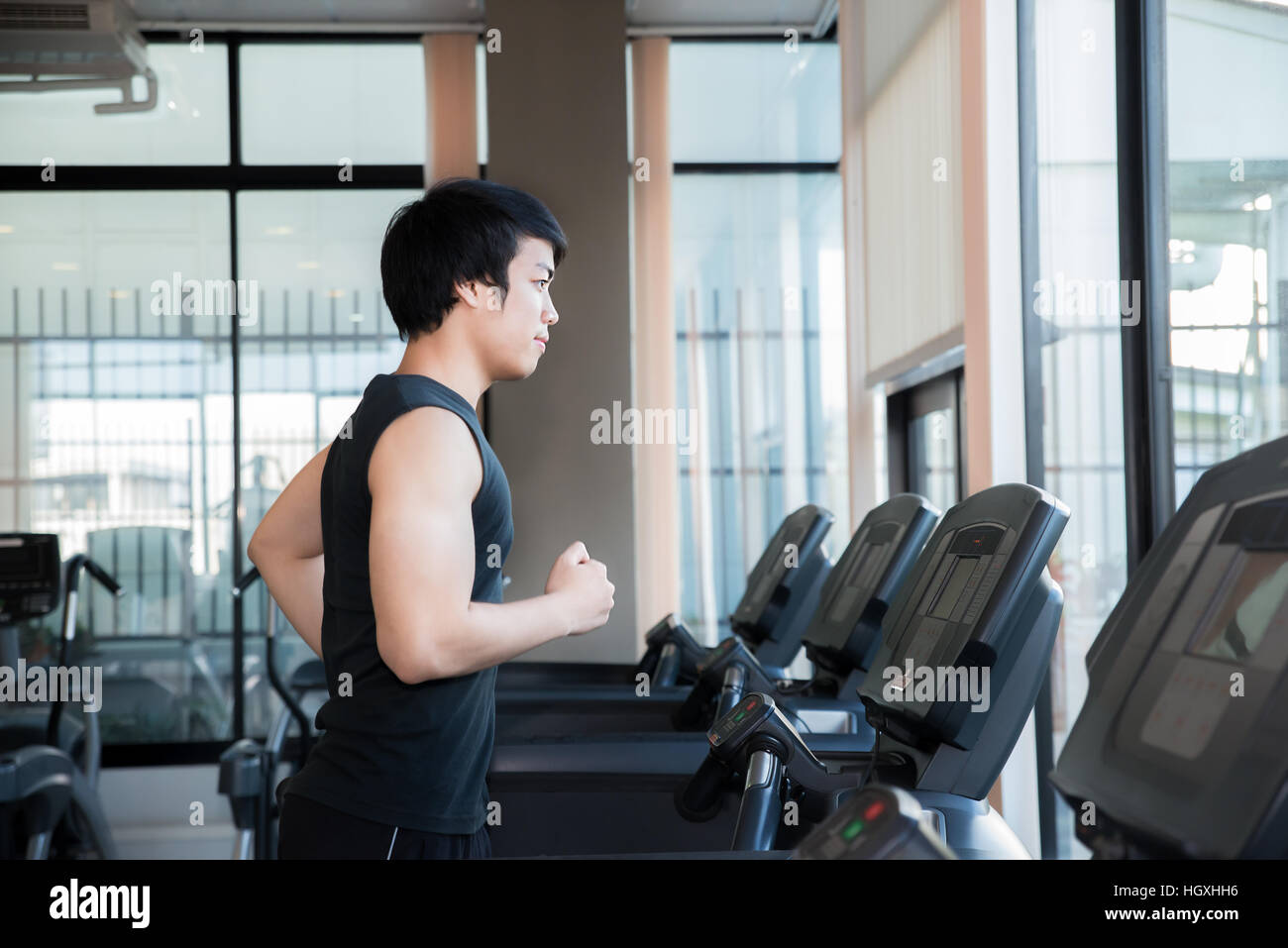 Asian young man running on treadmill in gym. Health and sport concept. Stock Photo