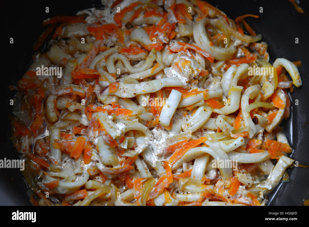 Calamaries stewed in cream sauce with carrots in pan Stock Photo