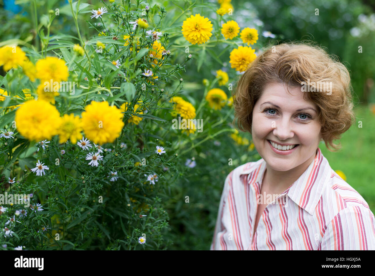 Smiling woman near yellow flowers in nature Stock Photo