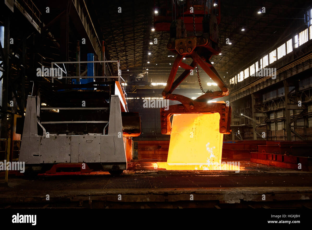 Steel Works - Crane delivers incandescent steel block to rolling mill Stock Photo
