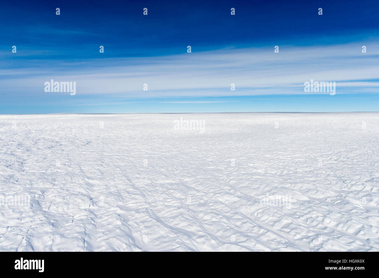 Layers of snow mask deep crevasse on the surface of the vast Greenland Ice Sheet plain. Stock Photo
