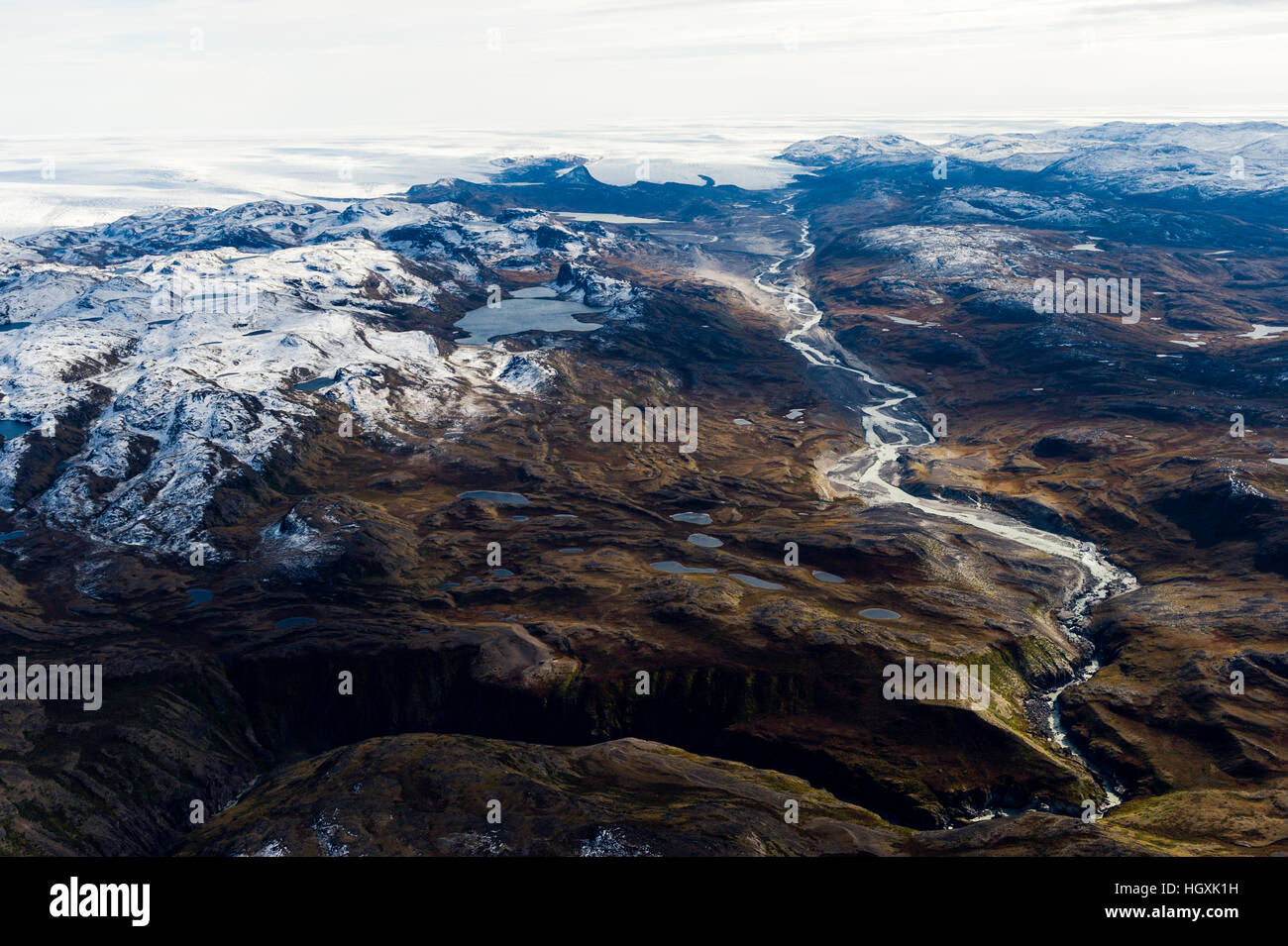 A winding river flows from a glacier and snakes it's way through a ...